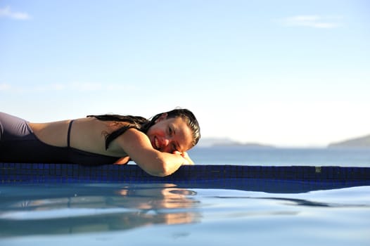 Woman relaxing on a swimming pool with a sea view
