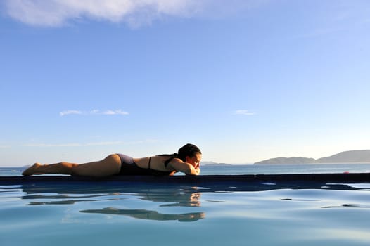 Woman relaxing on a swimming pool with a sea view
