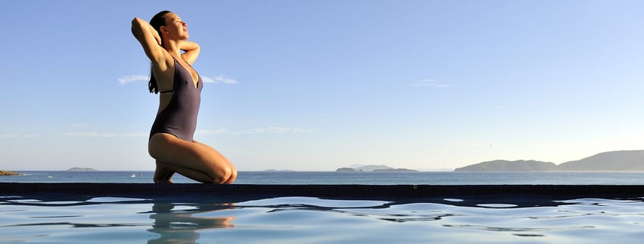 Woman relaxing on a swimming pool with a sea view 
