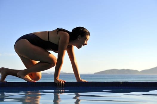 Woman relaxing on a swimming pool with a sea view 
