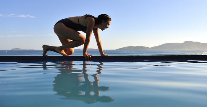 Woman relaxing on a swimming pool with a sea view 
