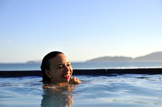 Woman relaxing on a swimming pool with a sea view 
