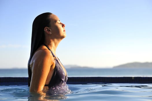 Woman relaxing on a swimming pool with a sea view 
