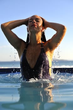 Woman relaxing on a swimming pool with a sea view 
