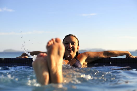 Woman relaxing on a swimming pool with a sea view 
