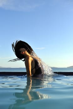 Woman relaxing on a swimming pool with a sea view 
