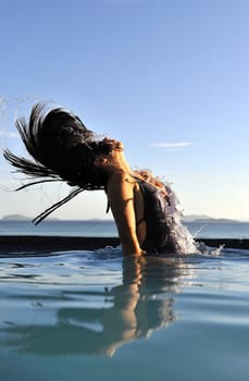 Woman relaxing on a swimming pool with a sea view 
