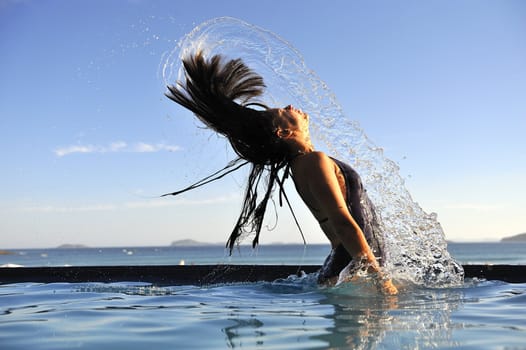 Woman relaxing on a swimming pool with a sea view 
