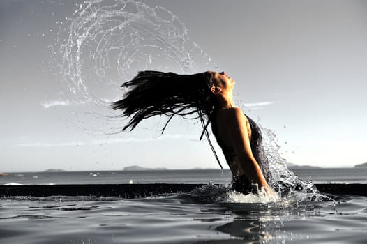 Woman relaxing on a swimming pool with a sea view 
