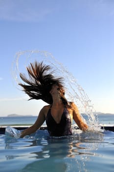 Woman relaxing on a swimming pool with a sea view 
