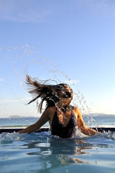 Woman relaxing on a swimming pool with a sea view 
