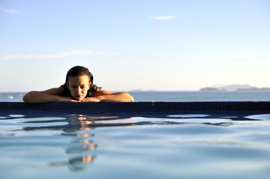 Woman relaxing on a swimming pool with a sea view 
