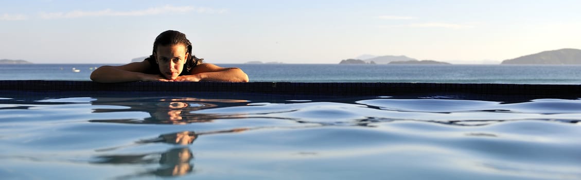 Woman relaxing on a swimming pool with a sea view 

