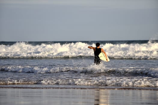 Surfer boy walking on the beach in Buzios, Brazil