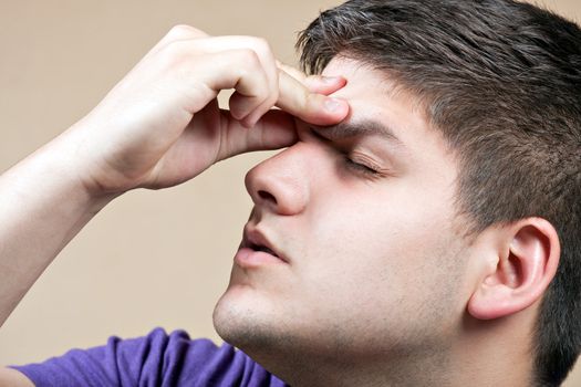 Young man has an intense headache. He might be experiencing stress during a time of economic crisis or other hardship.