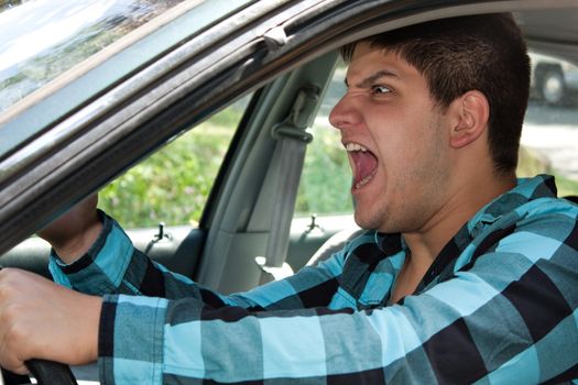 An irritated young man driving a vehicle is expressing his road rage.