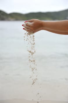 Woman dropping some sand in her hands