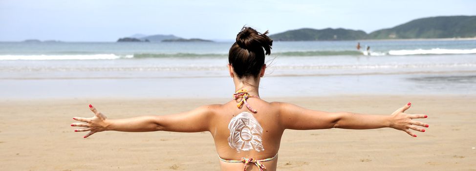 Woman taking sun with suncream draw on her back
