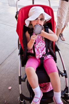 Cute little European toddler girl enjoying a piece of ice cream.