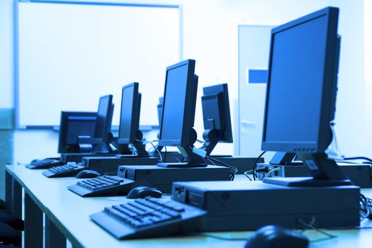 Room equipped with black computers. Image has blue tint.