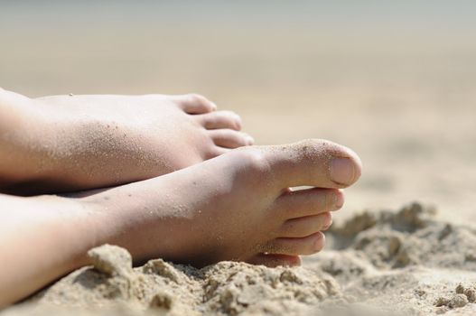 Shot of feet in the sand of woman relaxing at the beach.