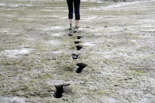 Girl walking barefoot trough mudflat in Brittany, France