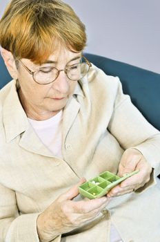 Elderly woman holding pill box with medication