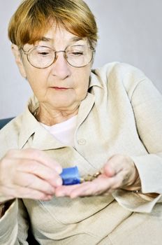 Senior woman pouring medication from pill bottle