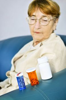 Elderly woman looking at pill bottles with medication