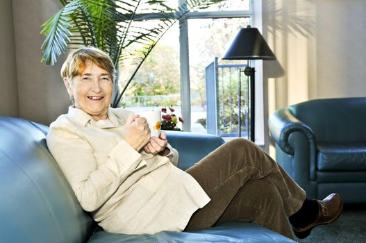 Senior woman sitting and smiling happily with cup of tea
