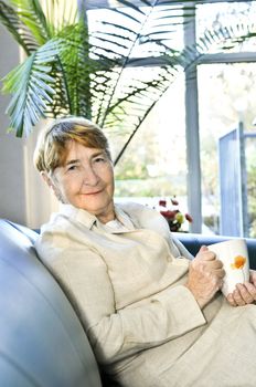 Senior woman sitting and smiling happily with cup of tea