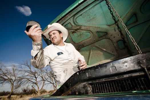 Man in cowboy hat under the hood of truck