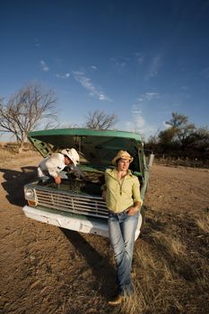 Man and woman in cowboy hats with old truck