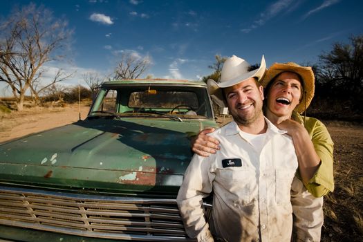 Man and woman in cowboy hats with old truck