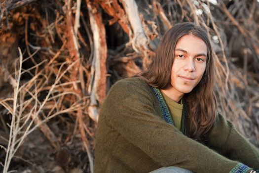Handsome young man with long hair in an outdoor setting