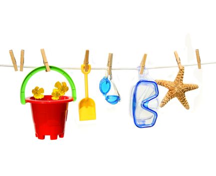 Child's summer toys on clothesline against white background