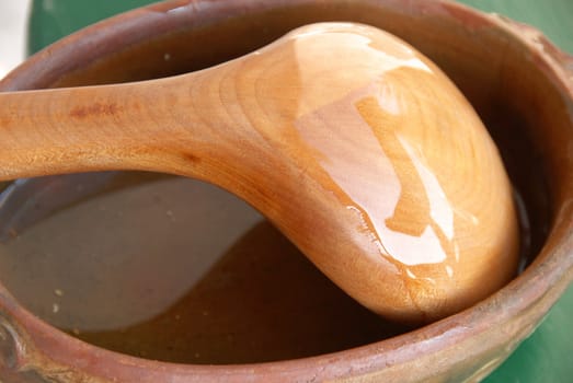 Yellow wooden spoon in brown earthenware closeup