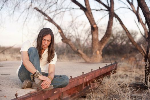 Handsome young man with long hair in an outdoor setting