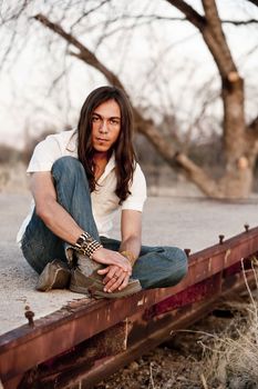 Handsome young man with long hair in an outdoor setting