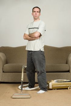 Full body view of a young man standing with his arms crossed, refusing to do anymore household chores
