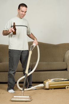 A young man drinking a beer while doing his household chores