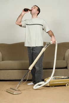 A man multitasking by drinking a beer and vacuuming the carpet