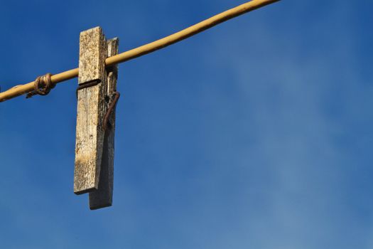 An Old weather worn and rusted clothespin on a clothes line against a dark blue sky