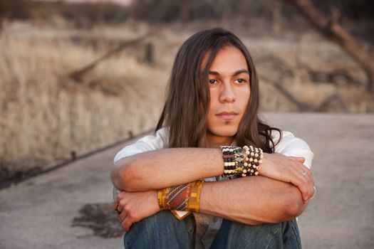 Handsome young man with long hair in an outdoor setting