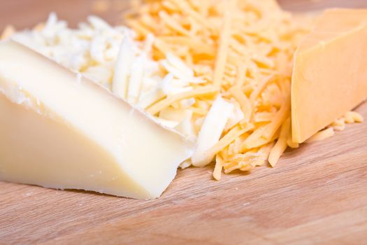 yellow and white cheddar cheese grated on a wood cutting board