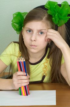 Girl with color pencils in hands and a sheet of paper