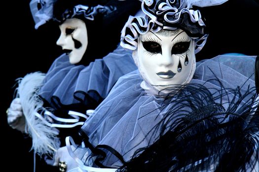 Two people dressed as Pierrot on black background, during the Venice Carnival