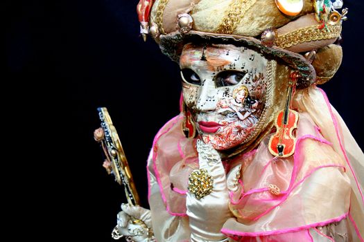 Lady with a mask covered with musical notes and a hand mirror during the Venice Carnival