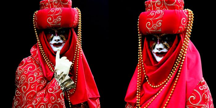 Two masked women, dressed in red on black background  at the Venice Carnival