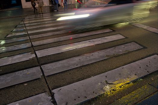 Car going through fast on a pedestrian crossing with motion blur